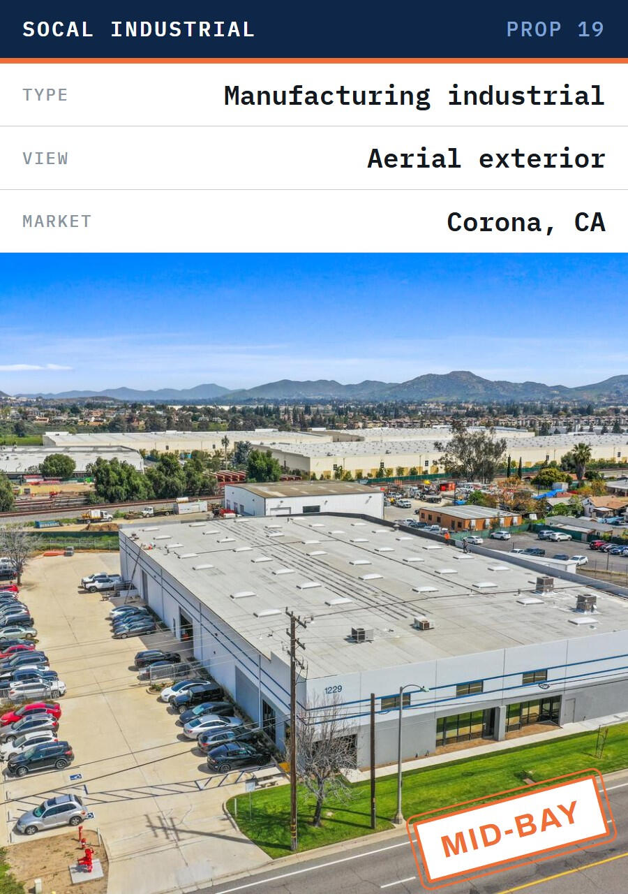 Corona CA mid-bay manufacturing industrial — Prop 19 commercial property Aerial of a mid-bay manufacturing industrial building in Corona, California, with parking and an industrial park beyond, commercial property subject to Prop 19 reassessment